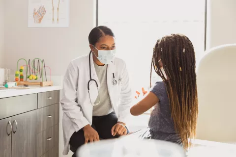 A doctor in a mask cares for a young patient