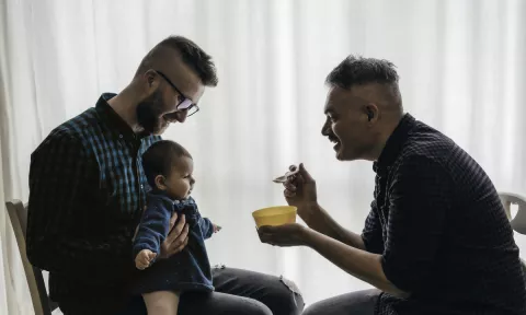 2 men feeding a baby