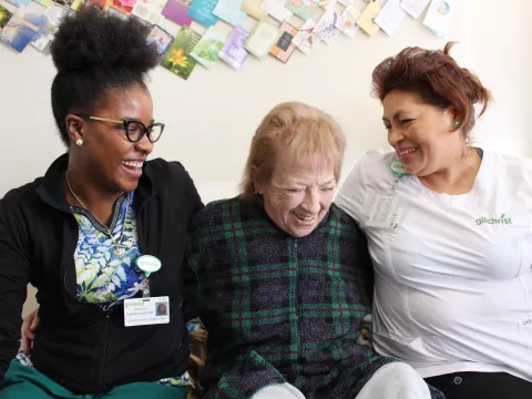 Health care providers supporting a patient, laughing and smiling together.