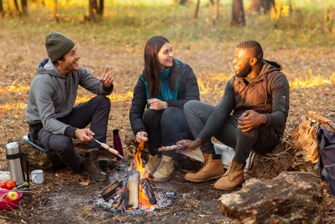 Friends gathered around a campfire in fall