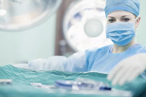 Woman in scrubs choosing tool from table