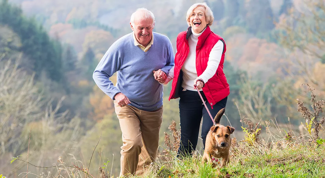 2 old people hiking with dog