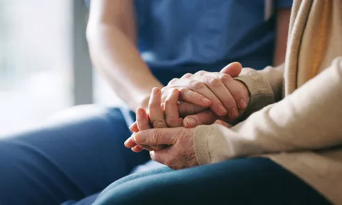 Two people with hands clasped together to provide support and care