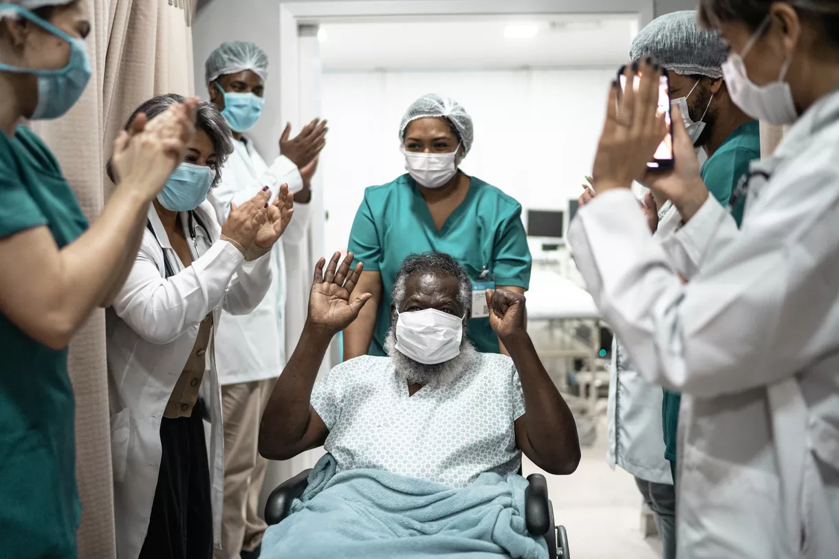 Patient in wheelchair being encouraged by medical team