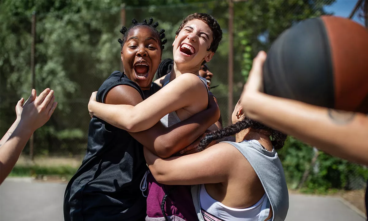 women hugging excitedly during outdoor basketball game