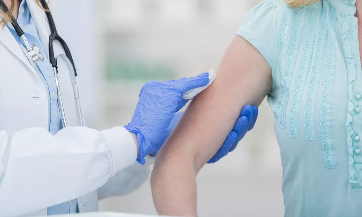 closeup of a woman's arm being wiped with alcohol swap