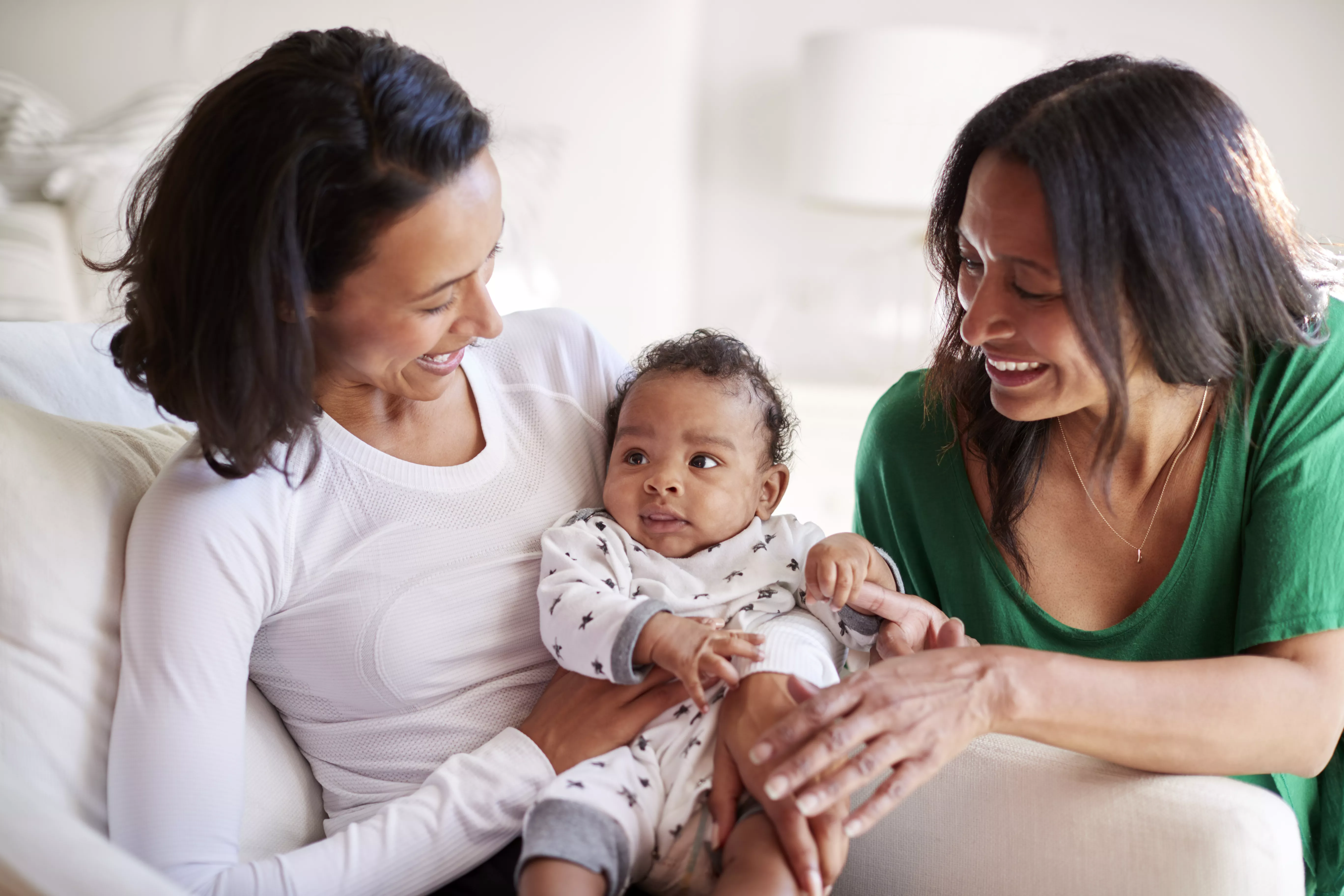 Two happy women adoring a baby