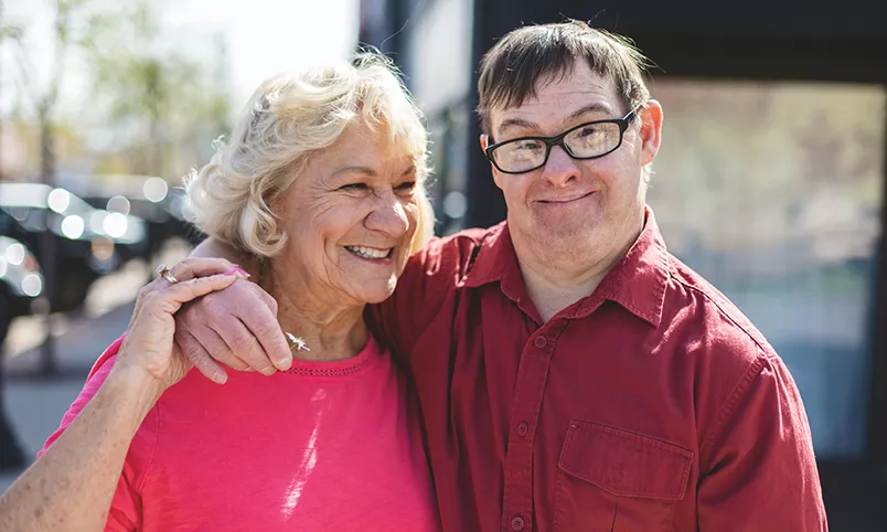 Senior woman and man with downs embrace