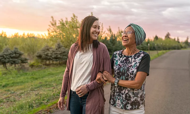 Woman and senior walking with arms linked
