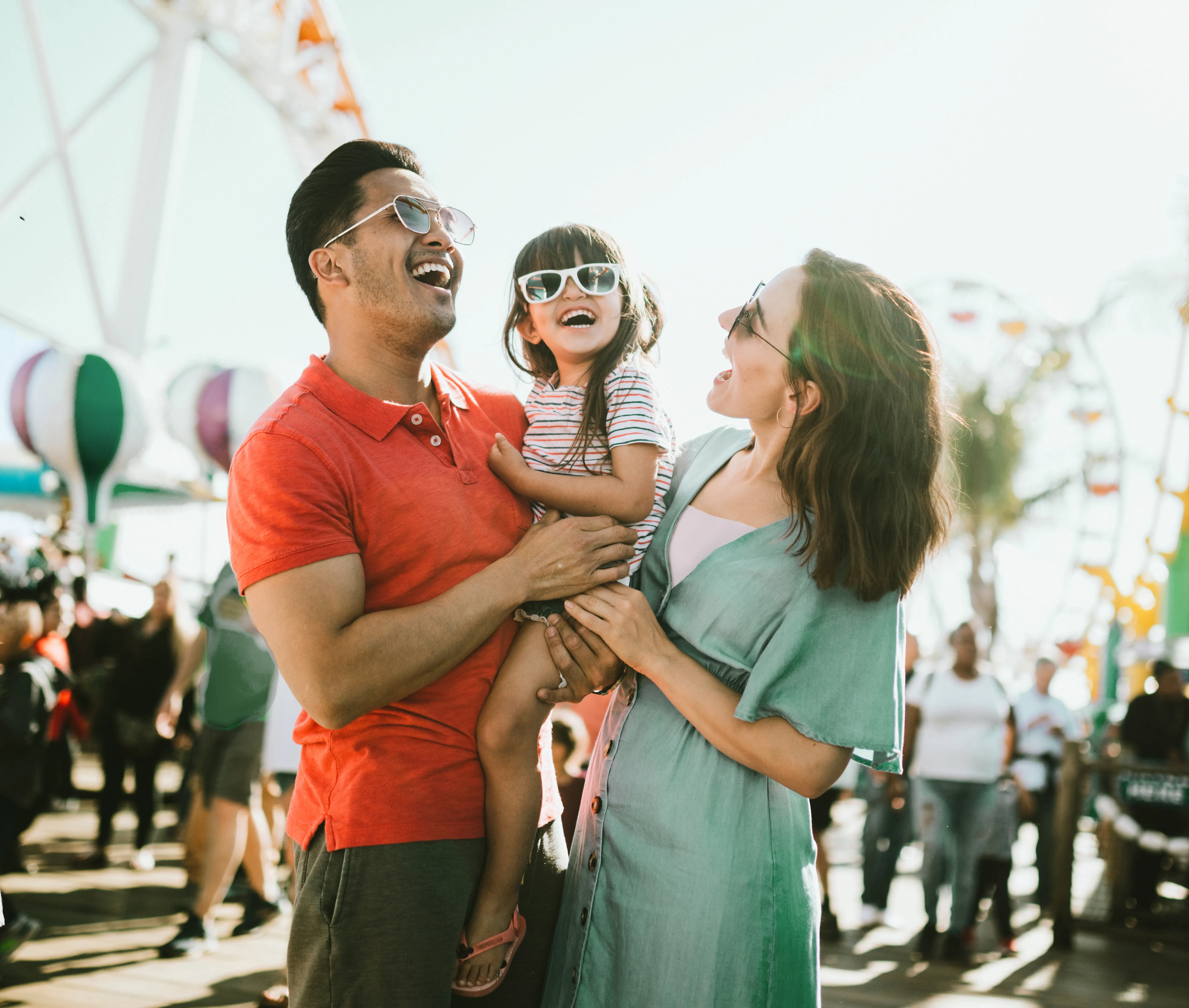 Smiling family at the fair, wearing sunglasses to protect their eyes in the summer sunshine.