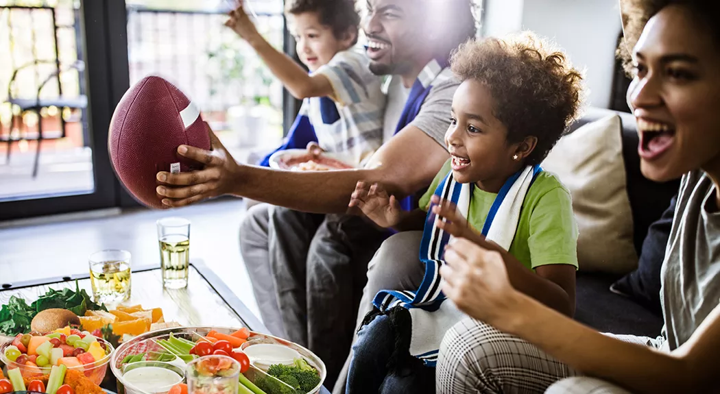 Family watching football while eating healthy snacks